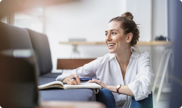 Zdjęcie przedstawia uśmiechnięta pośredniczke niruchomości, podczas potencjalnej rozmowy z klientem (poza kadrem)